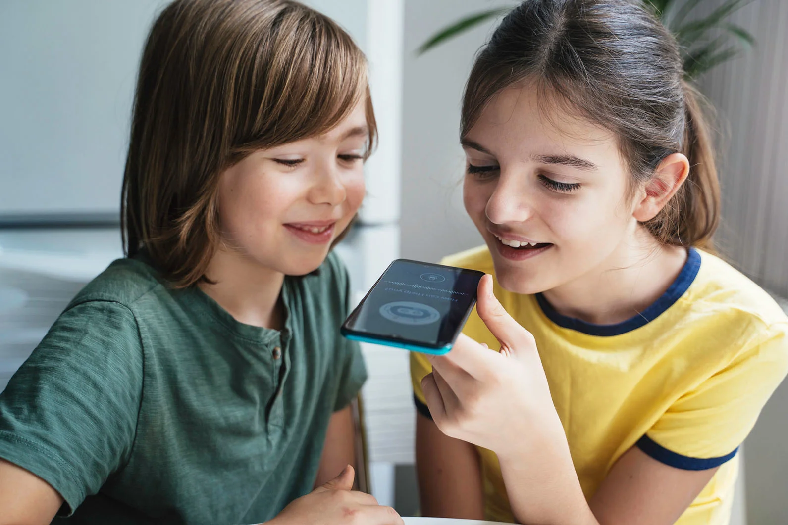 To børn taler ind i en smartphone, som optager deres lyd.