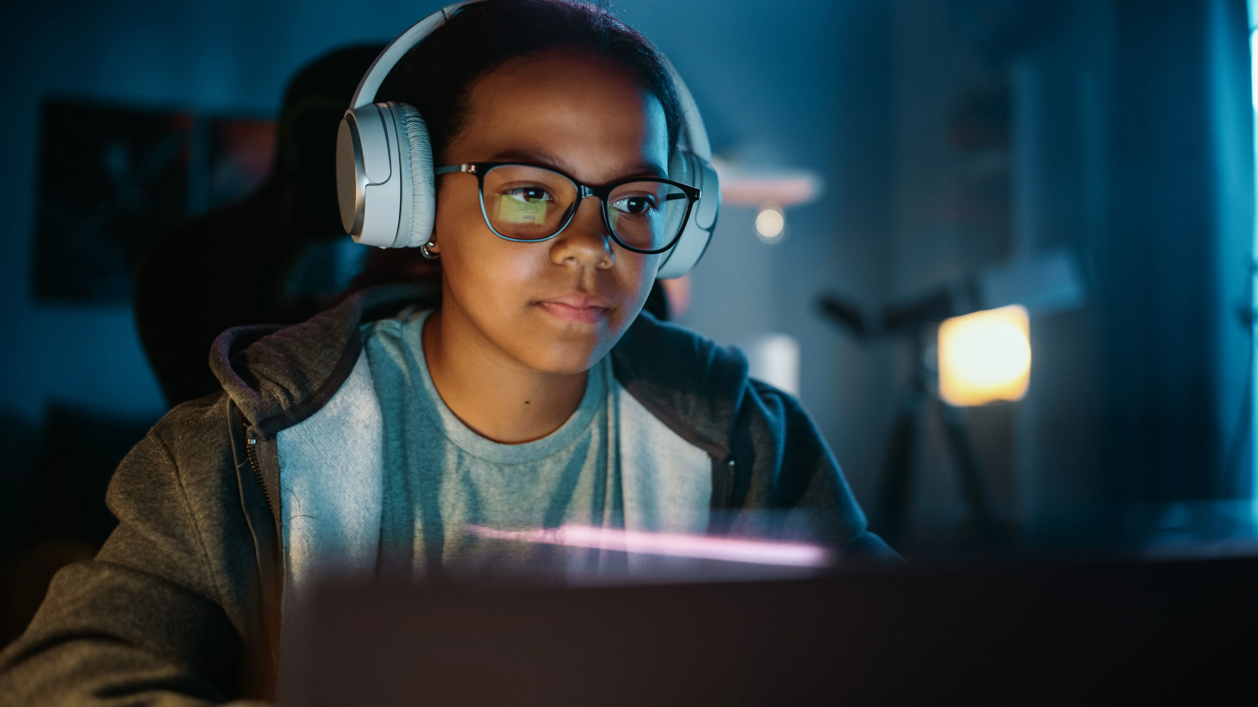 Pige sidder med høretelefoner på foran skærm