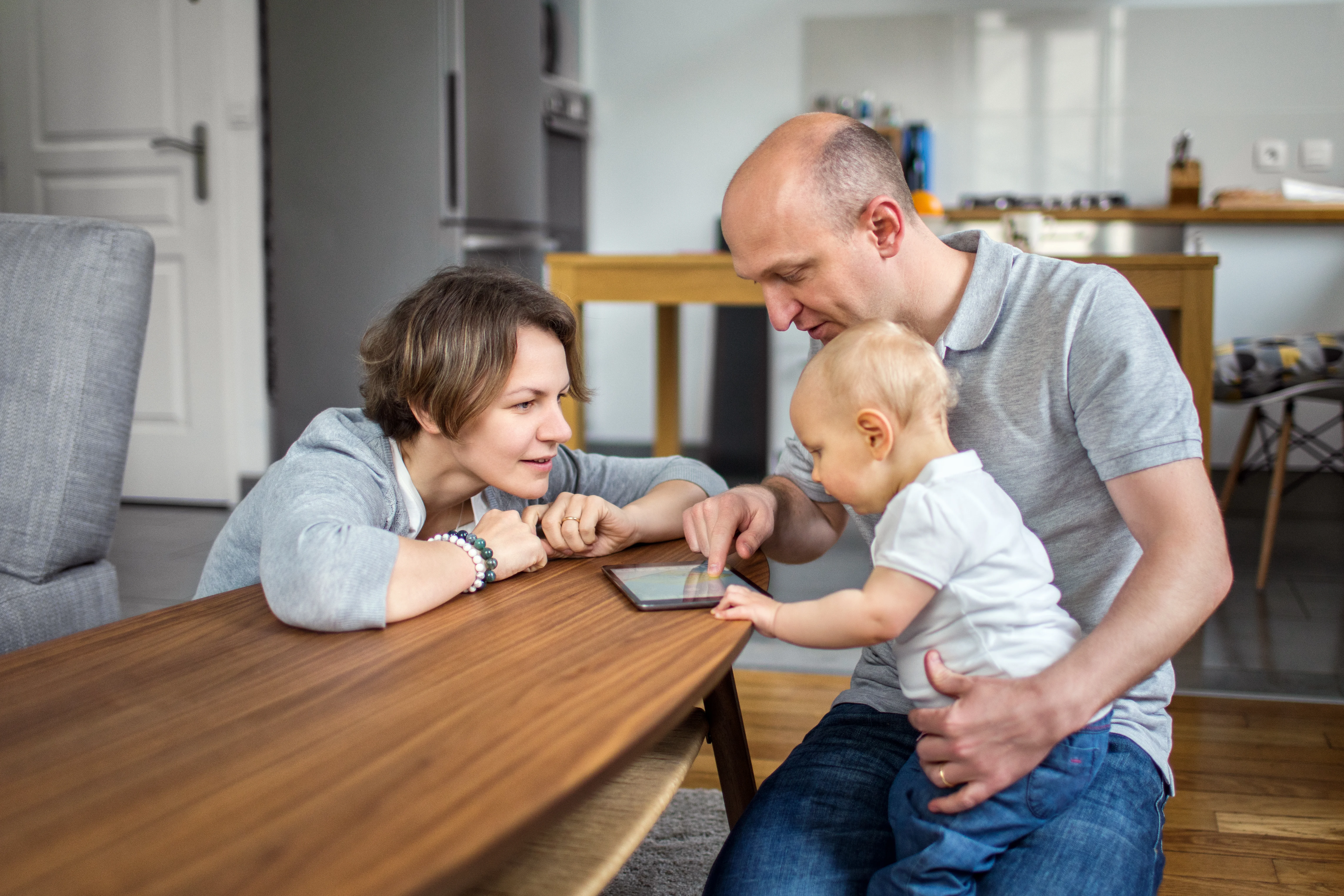 Forældrepar ser på iPad med deres lille barn.