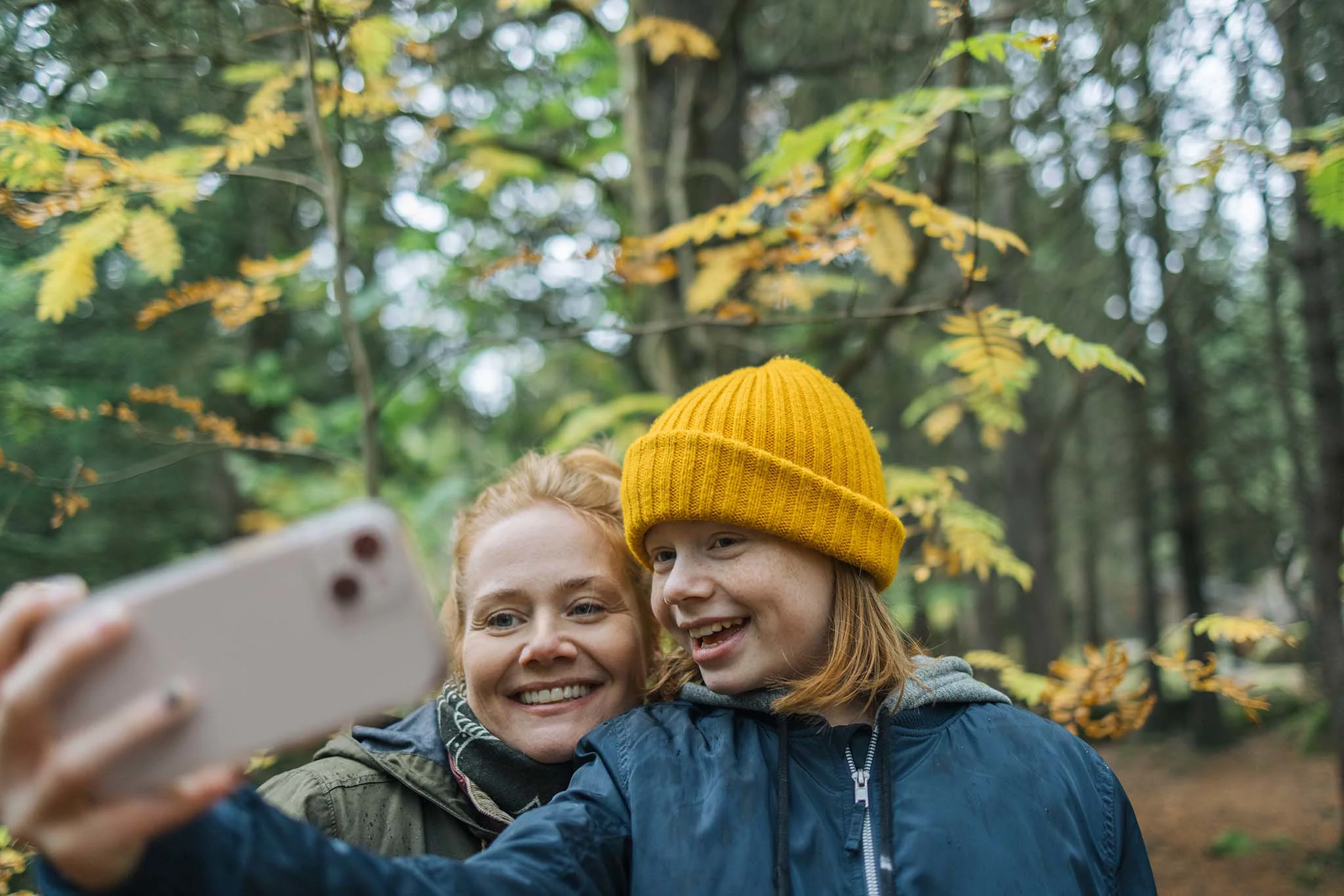 Mor og datter tager en selfie sammen i skoven.