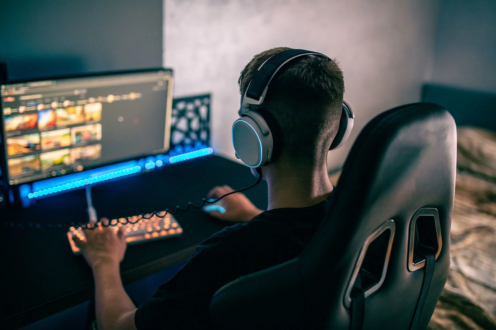 Teenagedreng sidder i gamerstil og spiller computer med høretelefoner på.