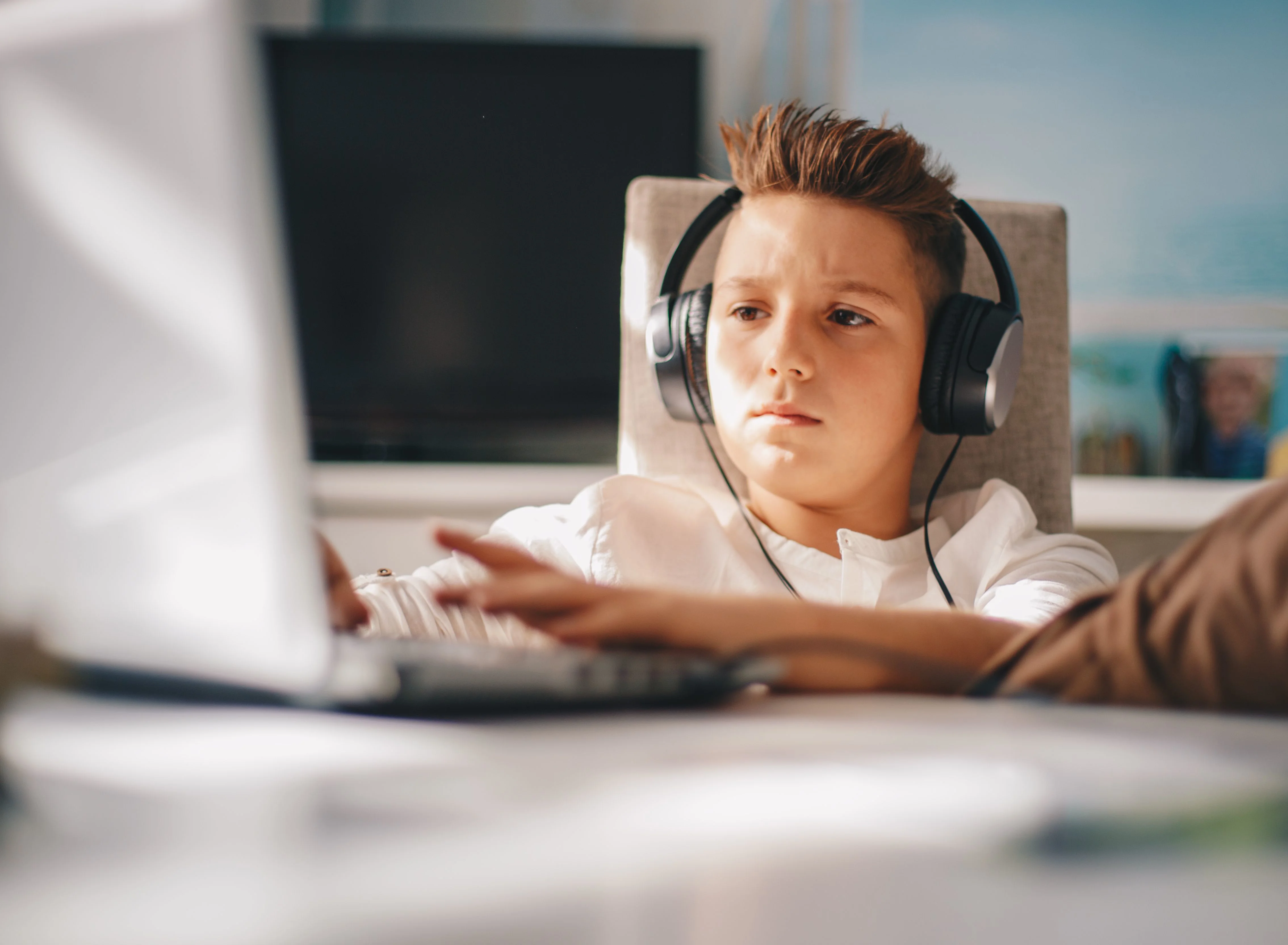 Dreng med høretelefoner på sidder og spiller computer