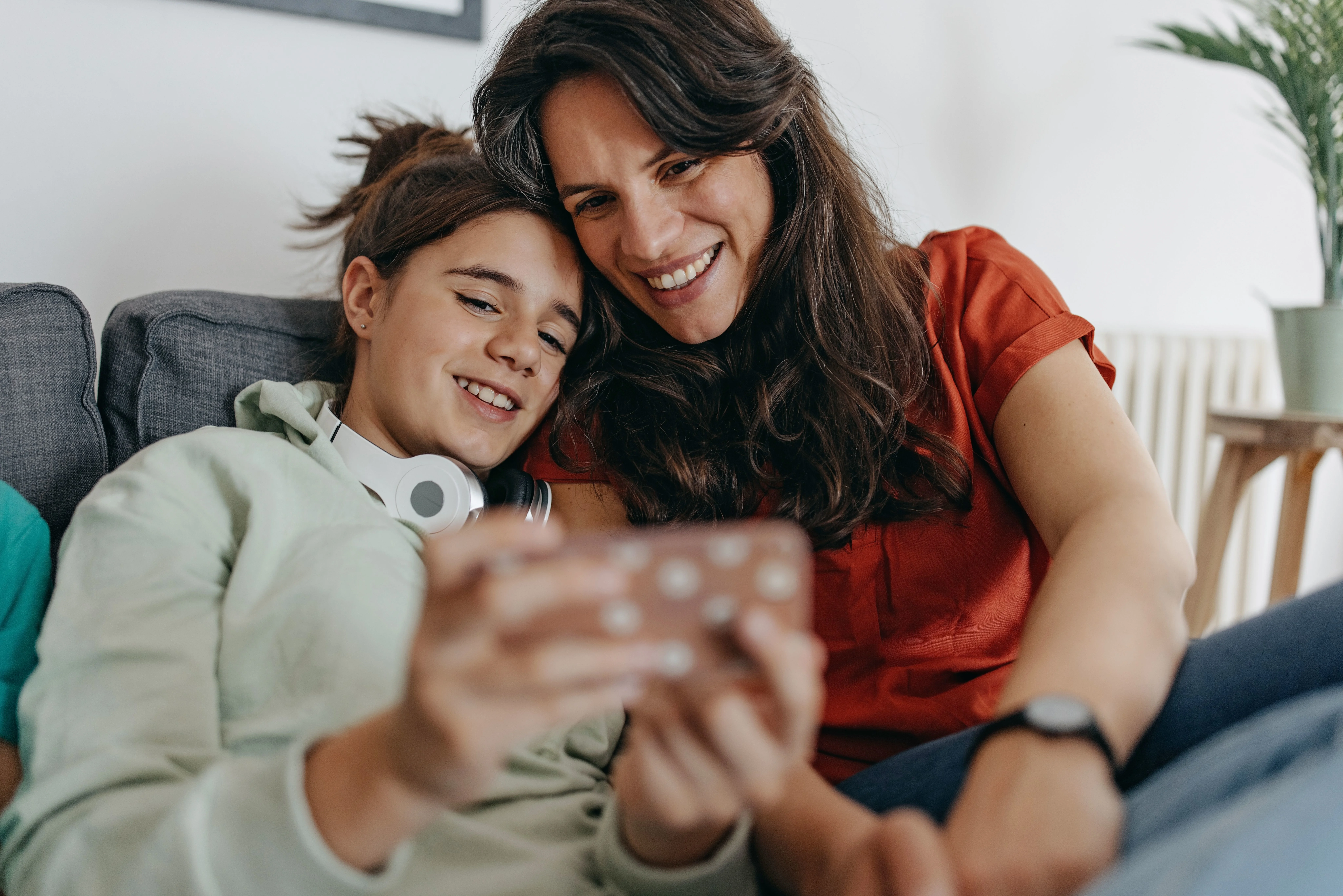 Dreng viser sin mor noget på sin smartphone. De smiler.